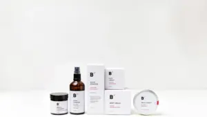 Minimalistiniai odos priežiūros produktų indeliai ant balto fono, reprezentuojantys grožio rutiną.